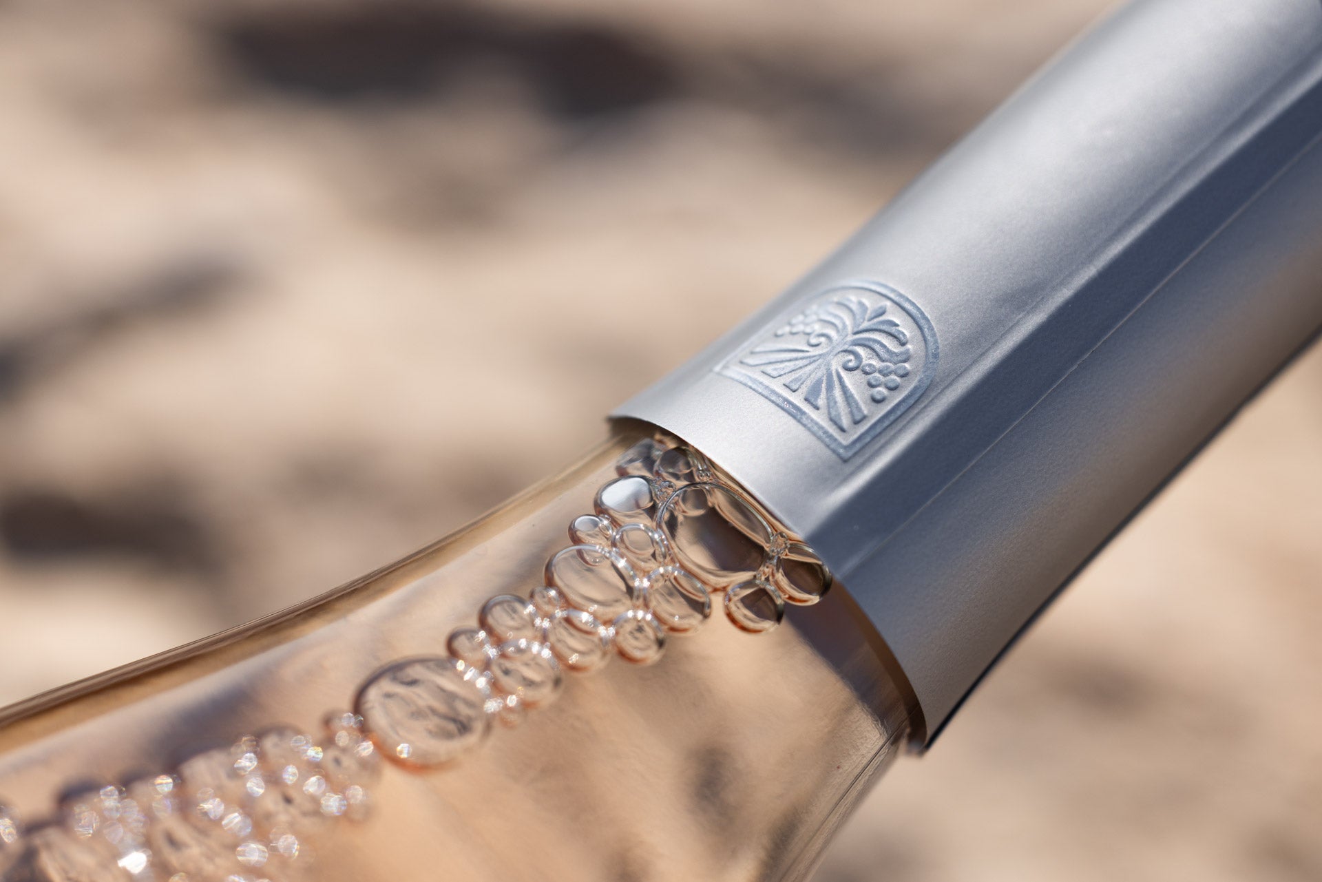 Close-up of Beau Viva rosé bottle neck with bubbles and foil seal