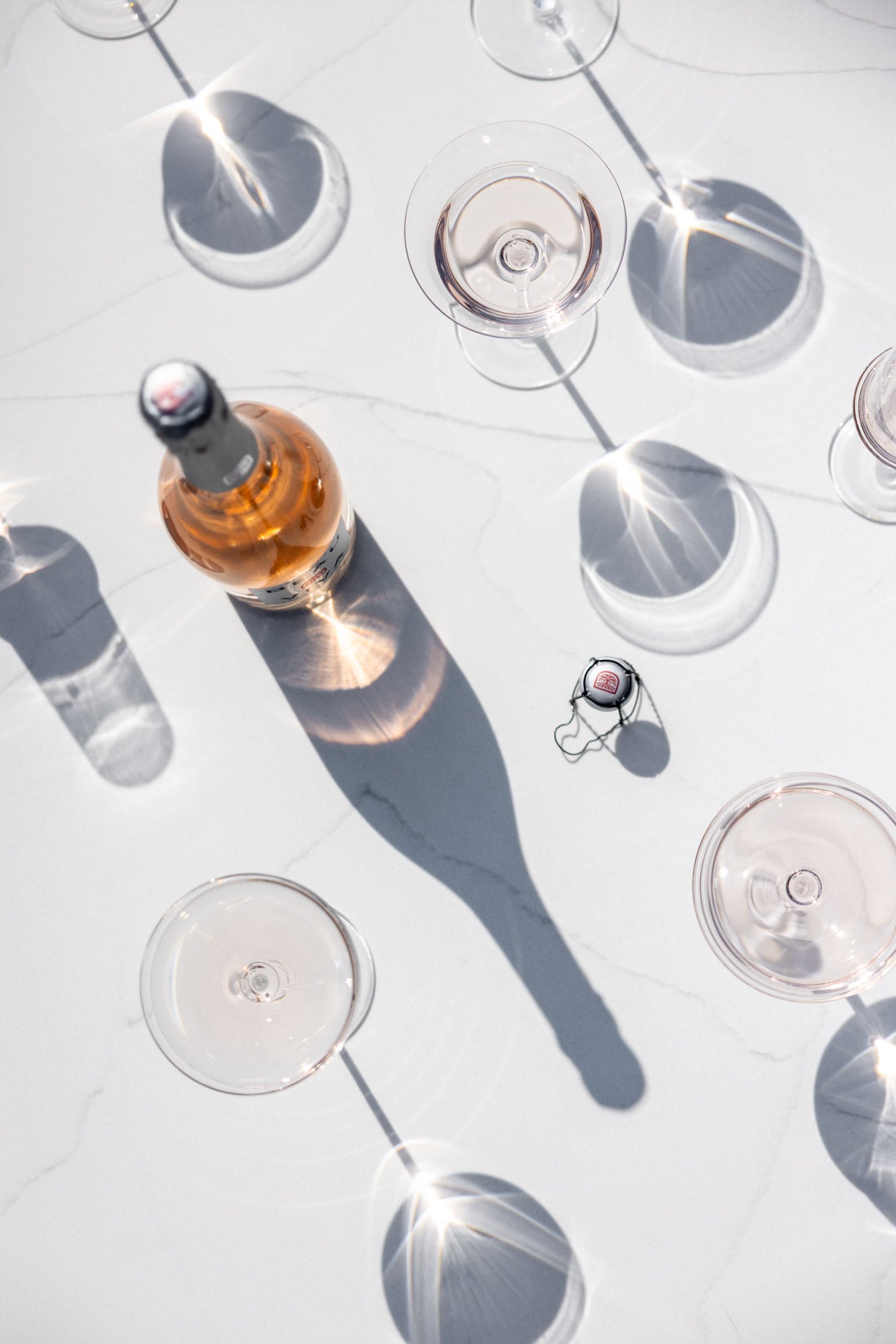 Flat lay of Beau Viva rosé bottle with glasses and shadows