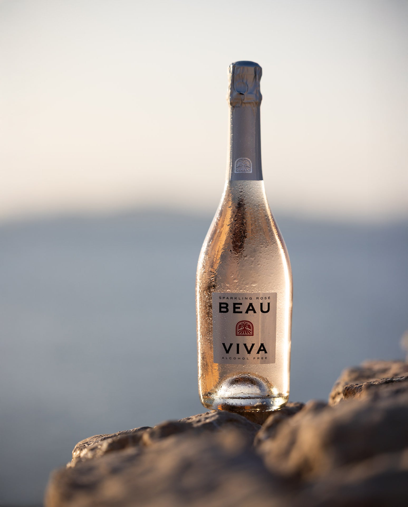 Beau Viva bottle by sea at sunset