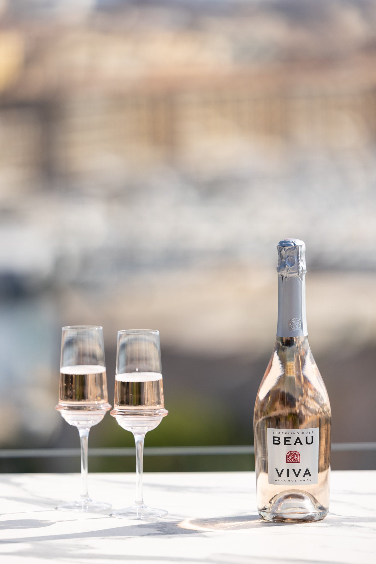 Beau Viva rosé bottle with two glasses on marble table